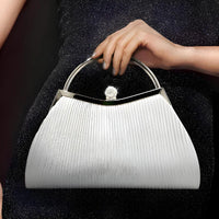Elegant white evening handbag with metallic handle held by woman in black dress