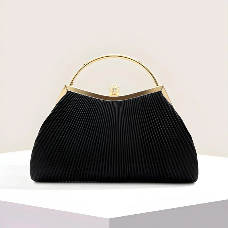 Elegant black pleated handbag with gold handle and clasp on a white display pedestal