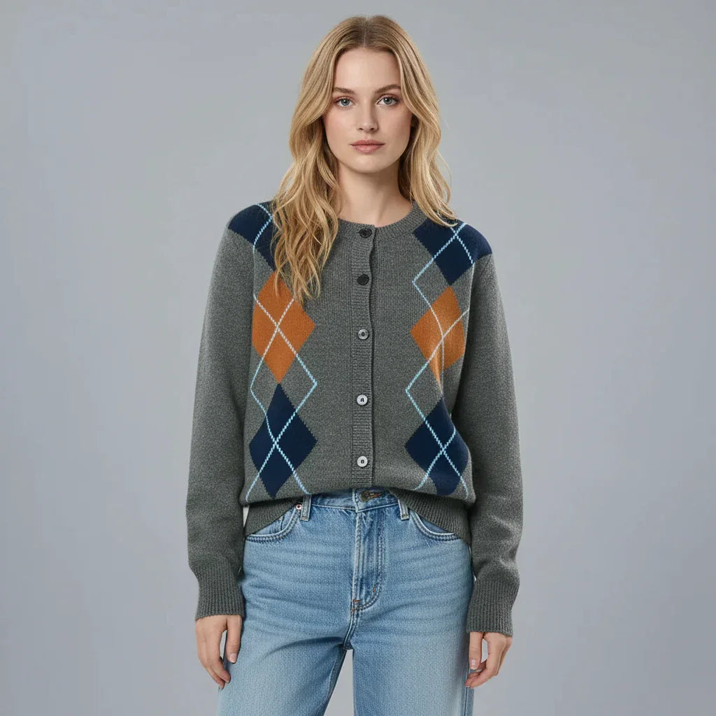 Person wearing a gray argyle sweater with blue and orange patterns on a plain background