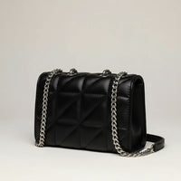 Black quilted leather shoulder bag with silver chain strap on light background