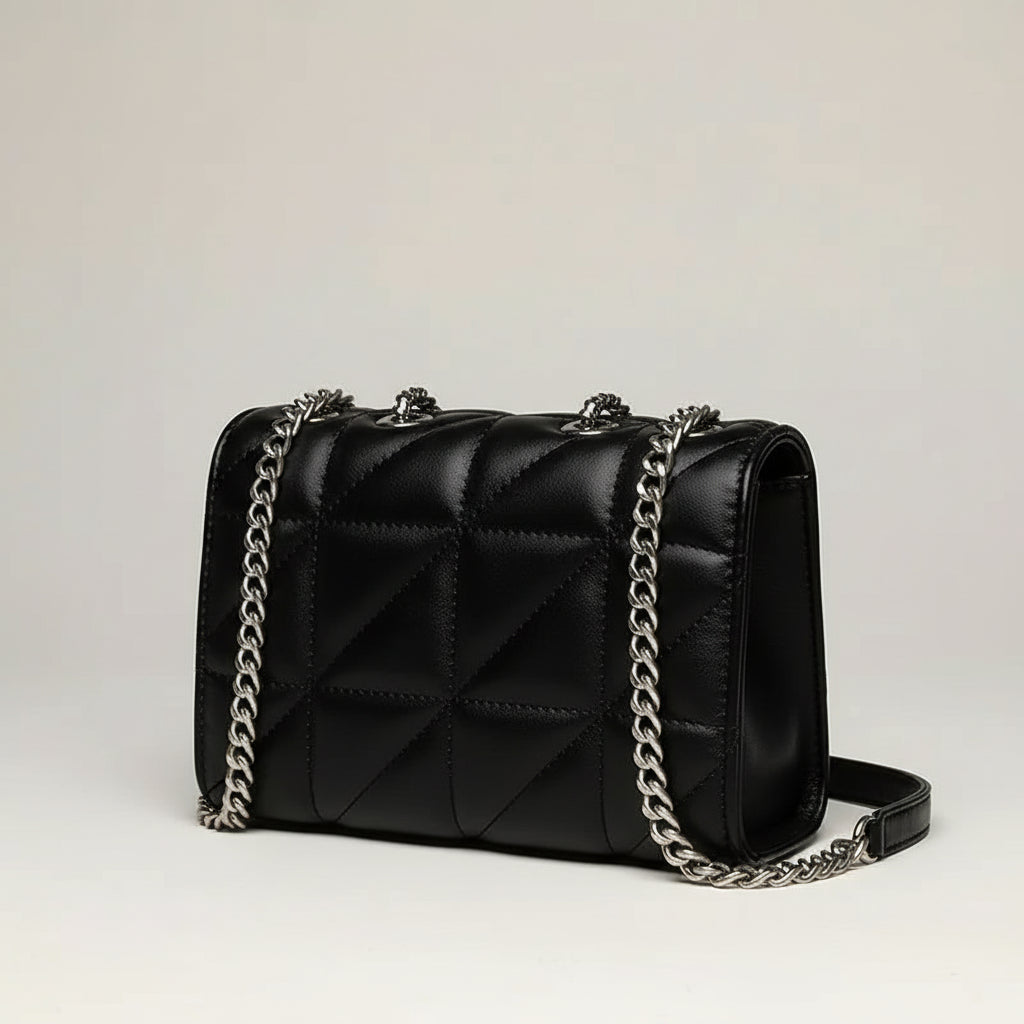 Black quilted leather shoulder bag with silver chain strap on light background