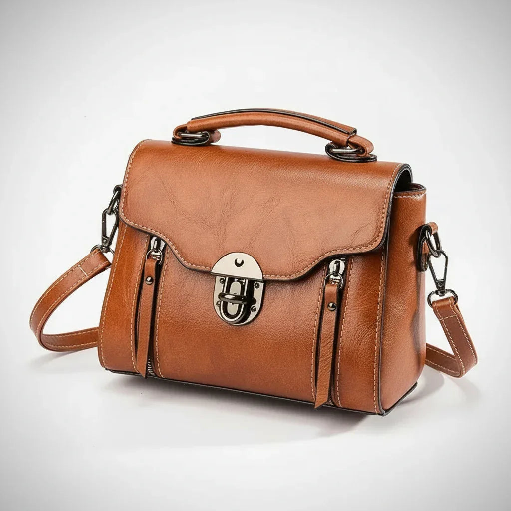Brown leather crossbody handbag with metal clasp and detachable strap on white background