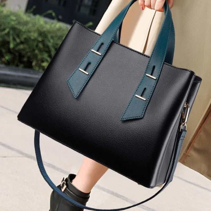 Woman holding black leather tote bag with blue handles outdoors