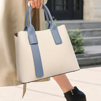 Woman carrying stylish beige tote bag with blue handles outdoors on steps