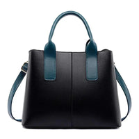 Black leather handbag with teal handles and shoulder strap on white background