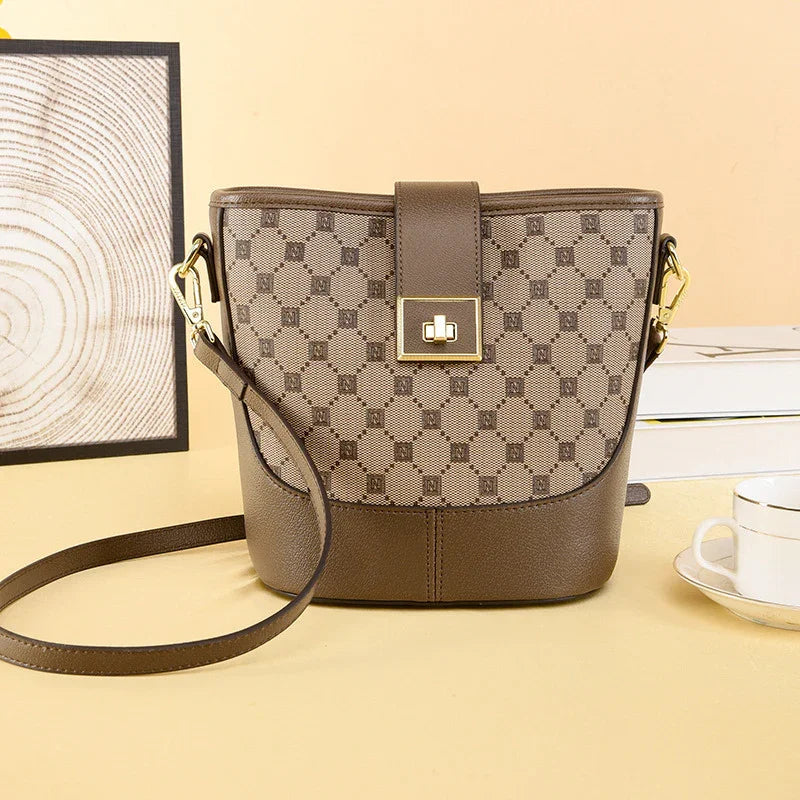 Brown leather crossbody bag with geometric pattern, gold buckle, on beige table