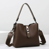 Brown leather handbag with top handle and adjustable shoulder strap on white background