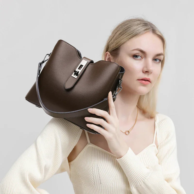 Woman holding brown leather handbag with metal clasp, fashion accessory on white background