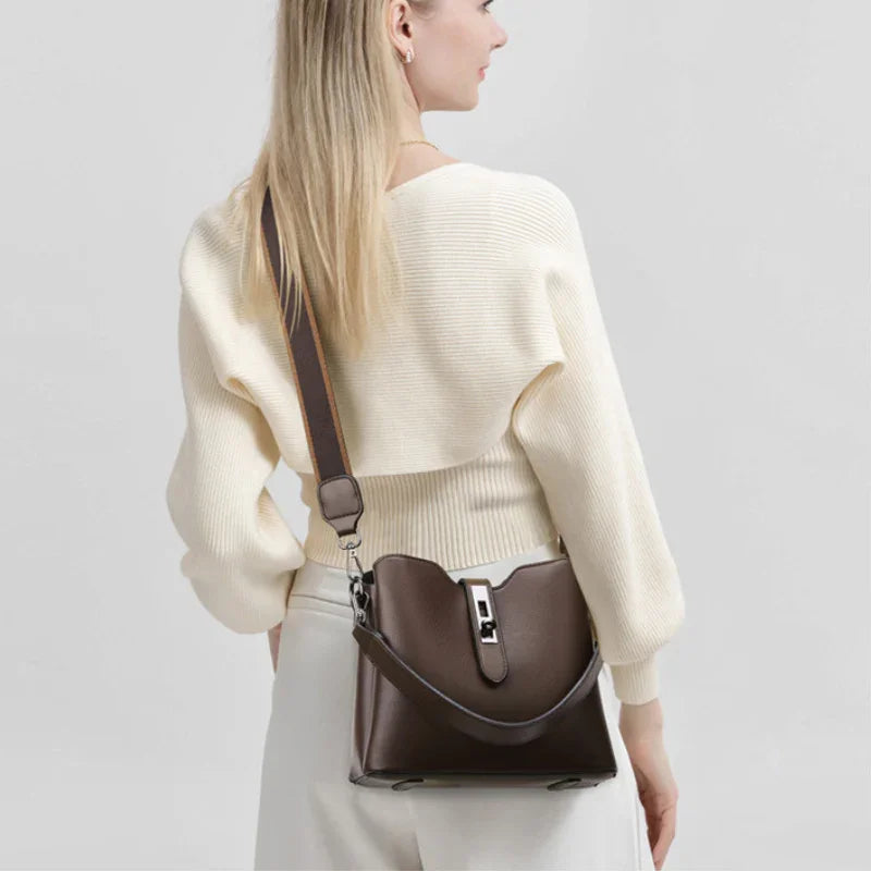 Woman in cream sweater with brown leather crossbody bag, minimalist background